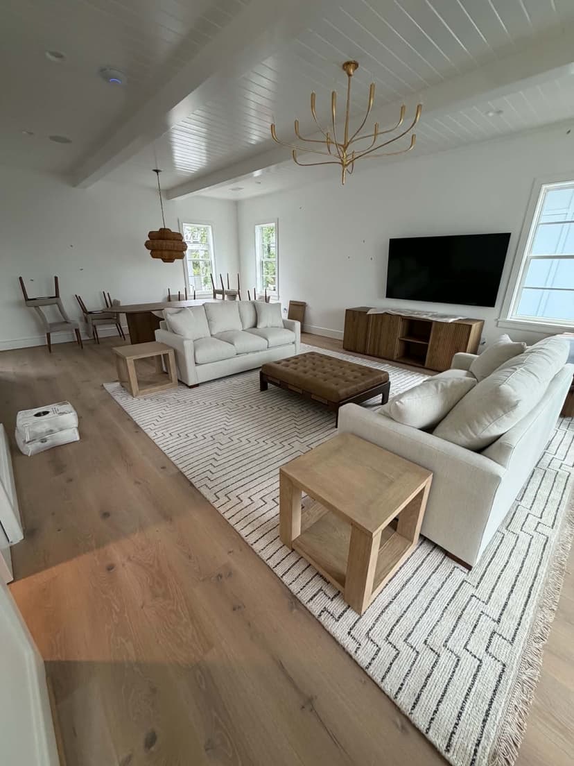 Fully furnished new-construction great room staged by Beach House Moving with sofas, ottoman, and dining set on 30A